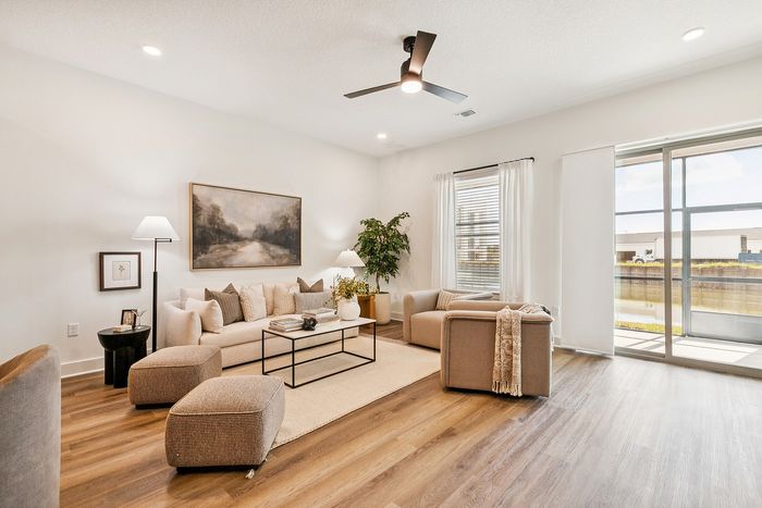Elegant living room with natural light, modern furnishings, and hardwood floors opening to a serene outdoor view.