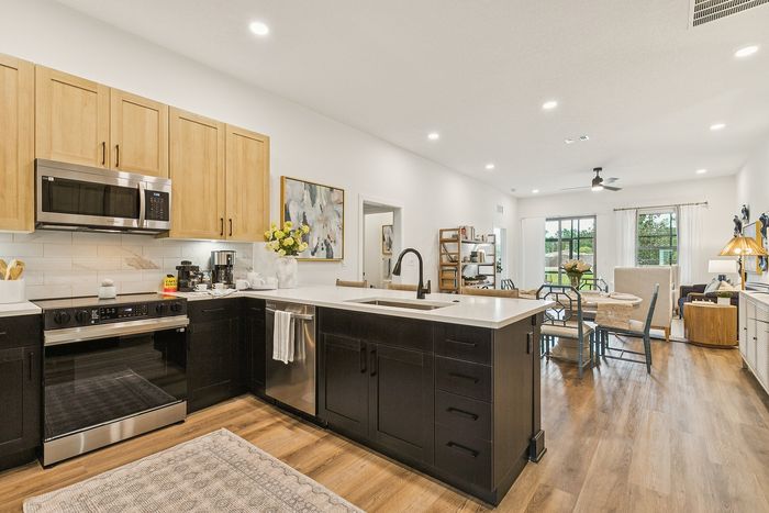 Inviting open-concept kitchen and living area with modern cabinetry, sleek appliances, and elegant dining space complemented by warm lighting.