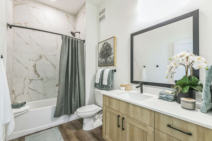 Elegant bathroom with modern fixtures, a large mirror, and stylish marble tiled shower.
