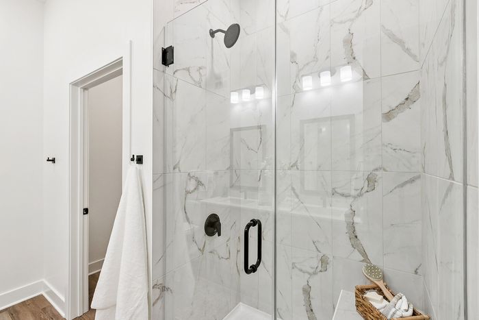 Luxurious bathroom with elegant marble tiles, modern glass shower, and chic black fixtures.