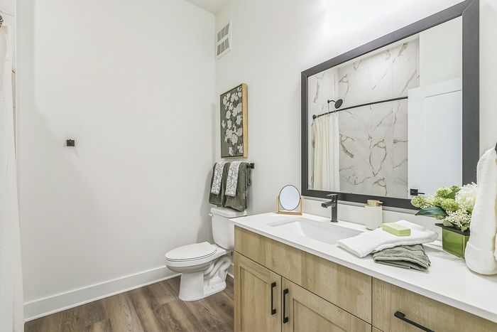 Elegant bathroom with modern fixtures, featuring a spacious vanity, large mirror, and stylish marble shower tiles.