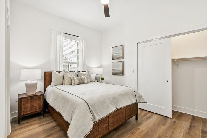 Bright and inviting bedroom with large window, cozy bed, and elegant decor in a modern apartment setting.