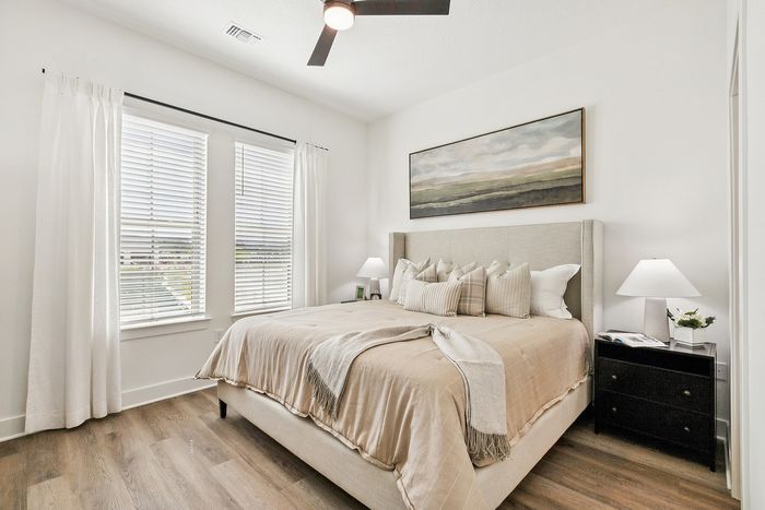 Bright and airy bedroom featuring a cozy bed with elegant bedding, large windows with natural light, and chic decor.