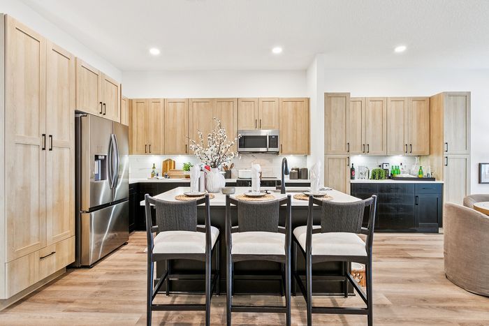 Modern kitchen with high-end stainless steel appliances, elegant wooden cabinetry, and a stylish island with seating for four.