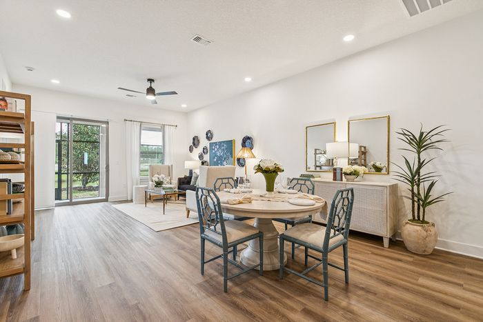 Bright and inviting open-plan living and dining area with elegant decor, featuring stylish wooden flooring, contemporary furniture, and abundant natural light from large windows.