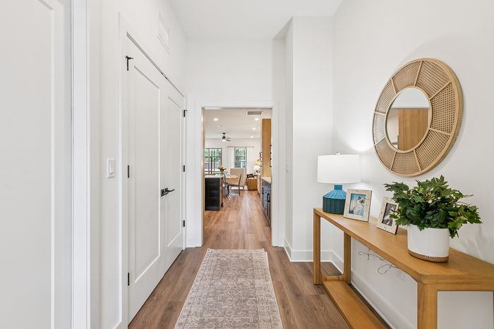 Bright and inviting hallway leading to a stylish open-plan living area, featuring elegant decor, wooden flooring, and modern lighting.