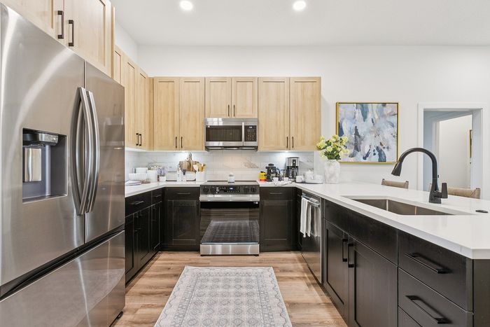 Modern kitchen with sleek stainless steel appliances, stylish light wood cabinets, and elegant countertops, offering a welcoming and functional cooking space.