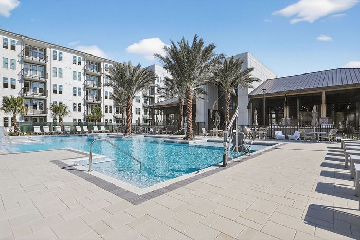 Luxurious apartment complex with a stunning outdoor pool area, surrounded by palm trees and modern amenities.