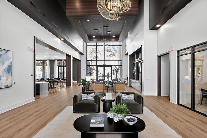 Luxurious modern lobby with high ceilings, elegant decor, and ample natural light, featuring stylish seating and a contemporary chandelier.