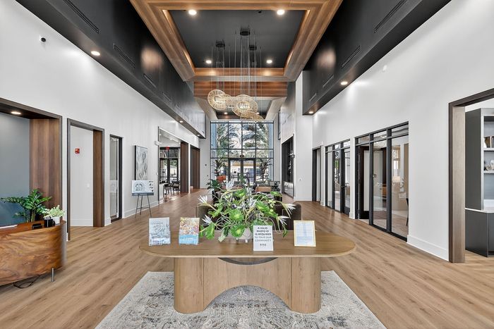 Elegant apartment lobby showcasing modern design with high ceilings, natural wood accents, and chic lighting fixtures, creating a welcoming atmosphere.
