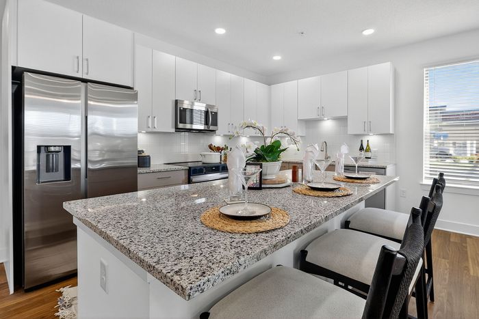 Modern kitchen with granite countertops, stainless steel appliances, and elegant dining setup, ideal for entertaining.