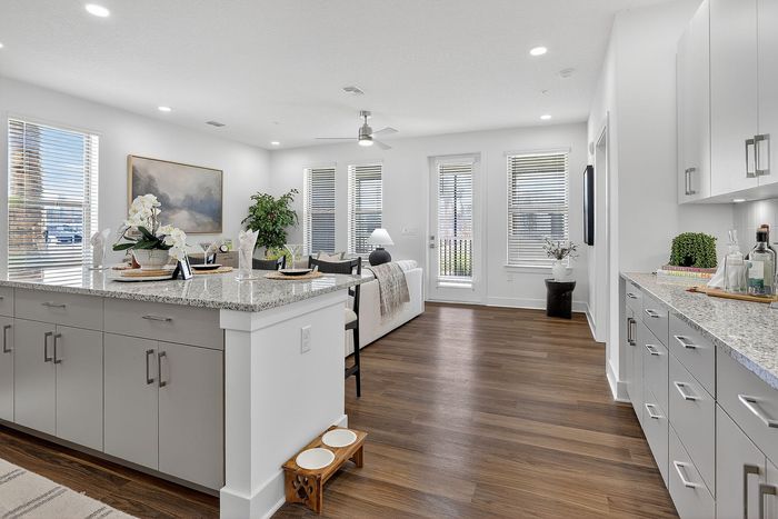 Elegant open-concept living area with a modern kitchen island, cozy seating, and abundant natural light, perfect for stylish living.