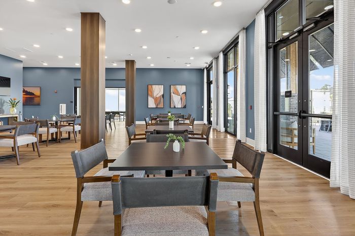 Modern dining area with elegant wooden furniture, large windows for natural light, and stylish decor creating a welcoming ambiance.