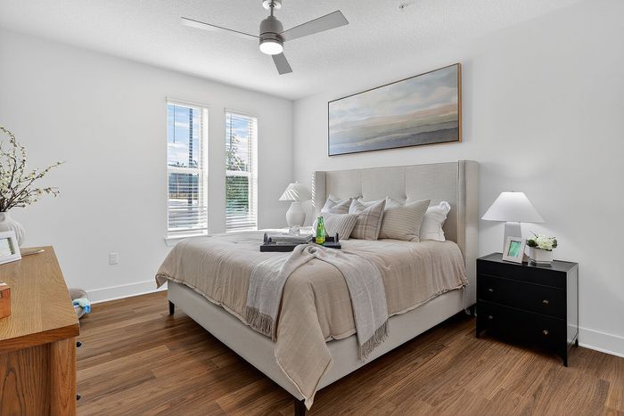 Elegant bedroom featuring a plush king-size bed, chic decor, and abundant natural light from large windows.