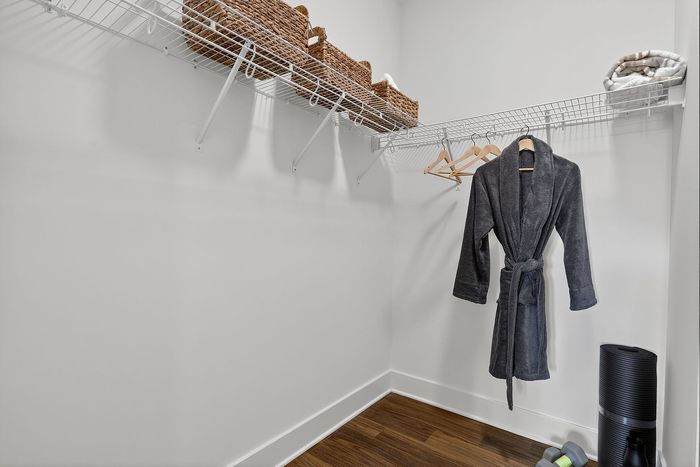 Spacious walk-in closet with elegant wire shelving, showcasing sleek storage baskets, plush robe, and fitness essentials.