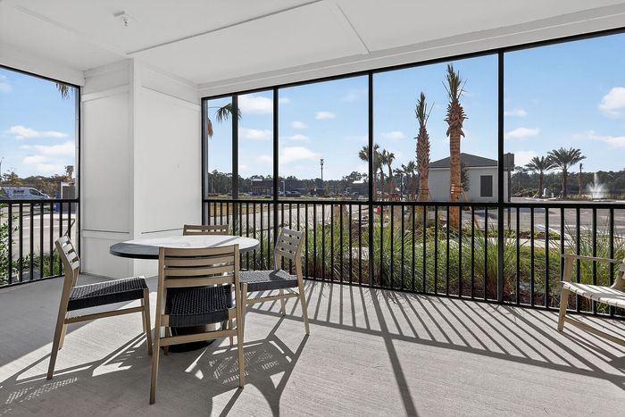 Bright and airy screened porch with stylish patio furniture, offering serene views of palm trees and landscaped outdoors, perfect for relaxation.