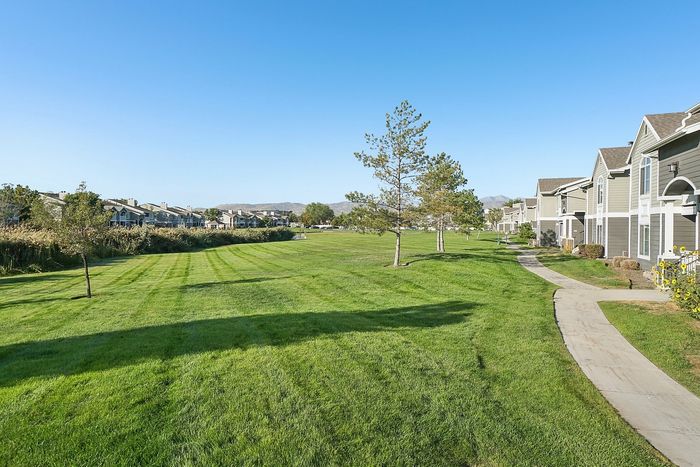 Charming row of modern apartments with scenic mountain backdrop, lush green lawns, and inviting walking paths.