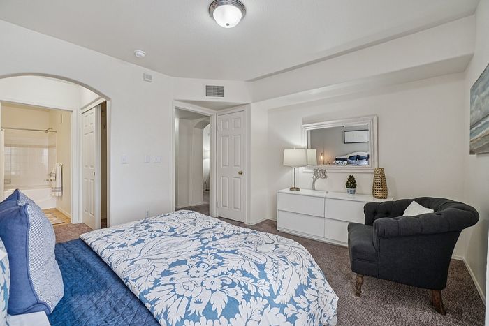 Elegant bedroom with plush bedding, stylish decor, and an inviting armchair; perfect blend of comfort and chic style.