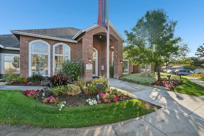 Charming apartment building with elegant brick facade, lush landscaping, and vibrant flower beds, creating an inviting curb appeal.