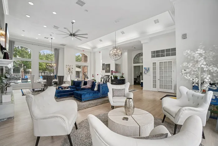 Elegant open-concept living area with luxurious seating and large windows, leading to a stylish dining space with a view.