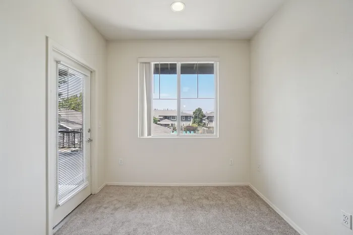 Bright, carpeted room with a large window offering scenic views and a cozy, inviting space.