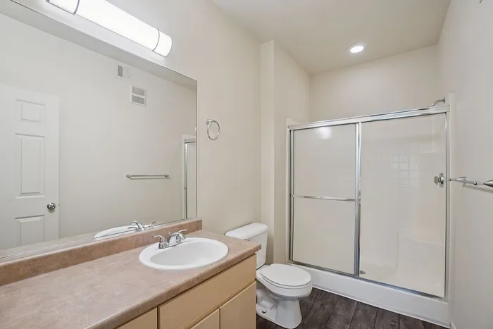 Modern bathroom with sleek countertops, large mirror, and elegant shower enclosure featuring clean and bright design.