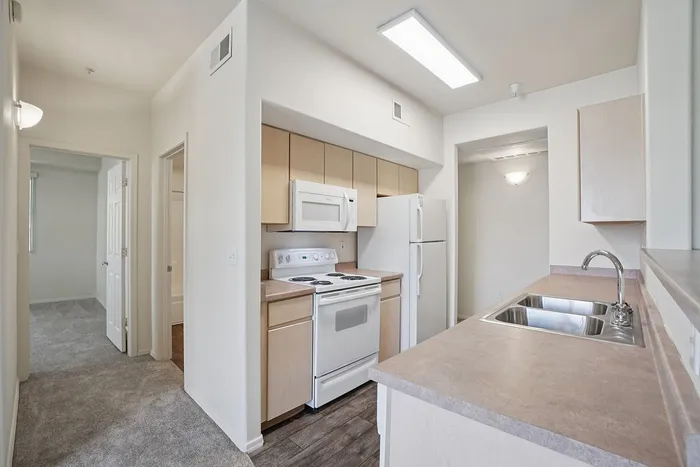 Bright, modern kitchen with sleek countertops, ample cabinetry, and contemporary appliances in a cozy apartment setting.