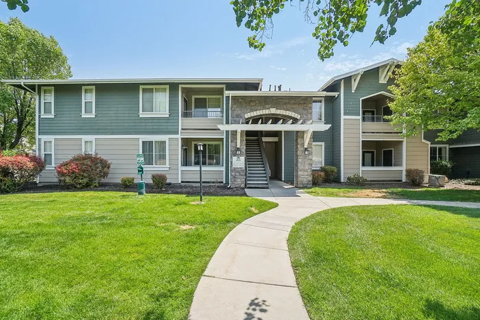 Charming apartment complex with lush green lawn and elegant entrance, featuring spacious balconies and surrounded by vibrant landscaping.