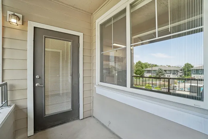 Inviting apartment balcony with modern railings offering scenic views of lush greenery and a sparkling pool area.