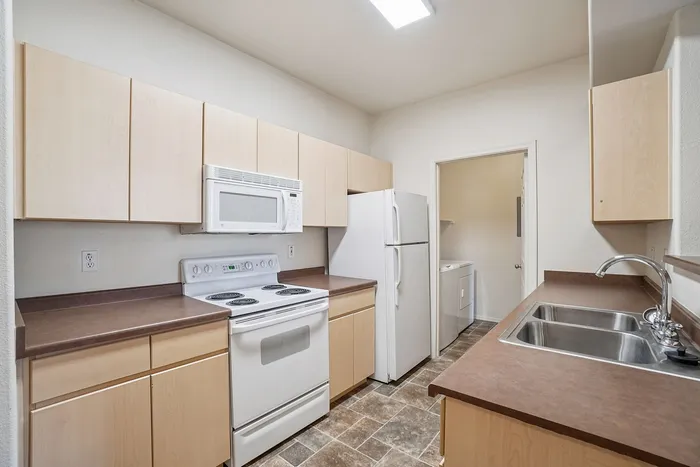 Modern kitchen with sleek countertops, ample cabinetry, and convenient appliances, leading to a compact laundry area.