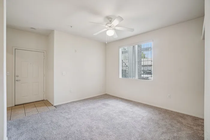Inviting apartment entryway with soft carpet, bright natural light, and a ceiling fan for comfort.