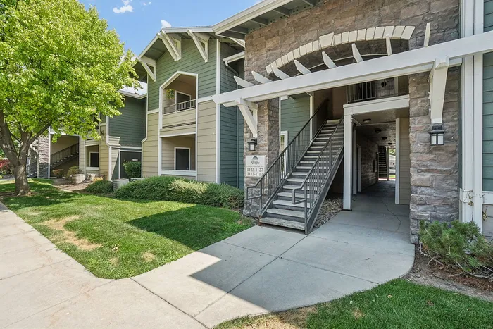 Charming apartment building with inviting stone accents and lush green surroundings, offering a welcoming and serene atmosphere.