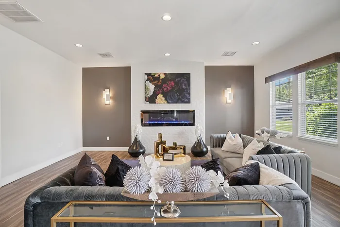 Elegant living room with stylish decor, featuring a cozy L-shaped sofa, modern fireplace, and large windows offering abundant natural light.