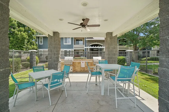 Charming outdoor patio with stylish seating, ceiling fan, and modern grills, ideal for entertaining in a lush, landscaped setting.