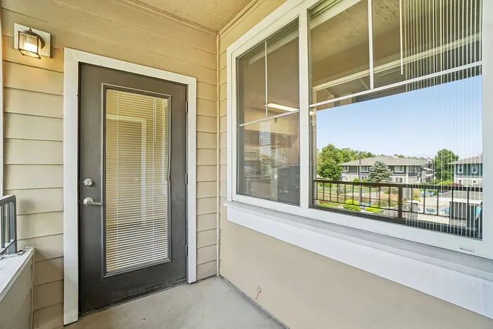Bright and inviting apartment balcony with modern glass door and views of a serene landscaped courtyard.
