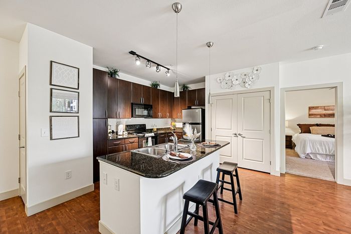Modern open-concept kitchen and living area with sleek wooden cabinetry, granite countertops, and cozy decor, perfect for stylish urban living.