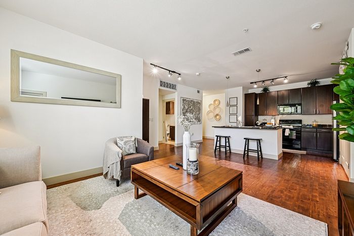 Chic open-concept living space with elegant hardwood floors, modern kitchen with black cabinetry, and cozy seating area.