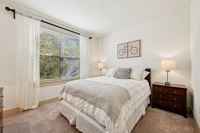 Bright and inviting bedroom with a cozy bed, elegant decor, and large window with lush garden view.