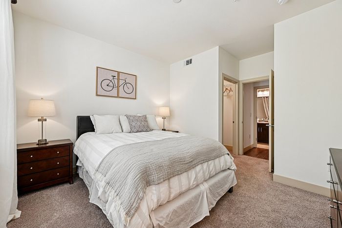 Inviting bedroom with cozy bed, stylish decor, and natural light illuminating a tranquil ambiance.