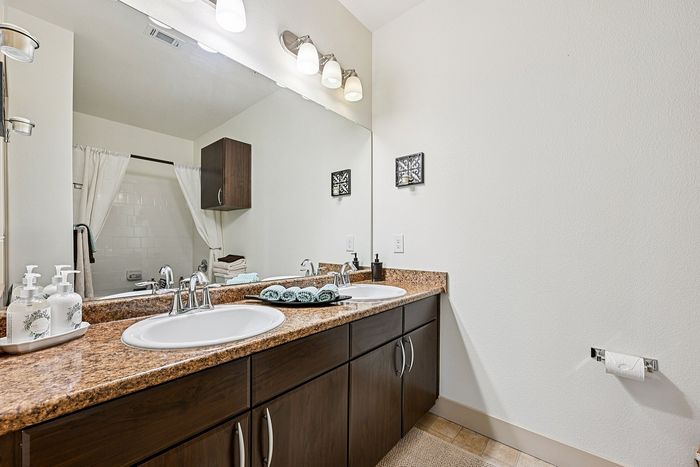 Elegant bathroom featuring dual sinks, polished granite countertops, and ambient lighting with clean, contemporary design.