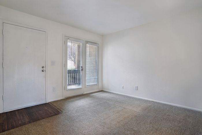 Inviting living space with plush carpeting and elegant French door leading to an outdoor patio with view.