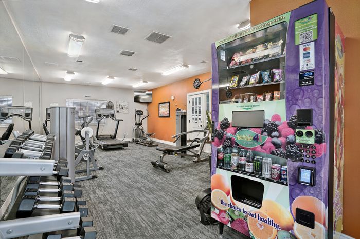 Modern fitness center equipped with treadmills, weights, and a vibrant vending machine offering healthy snacks.