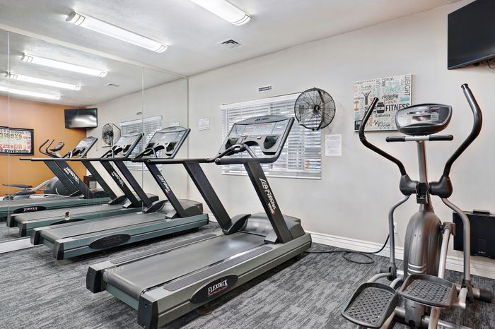 Modern fitness center with state-of-the-art treadmills, elliptical machine, and vibrant motivational decor.