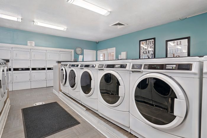 Modern laundry room featuring rows of high-efficiency washers and dryers, brightly lit.