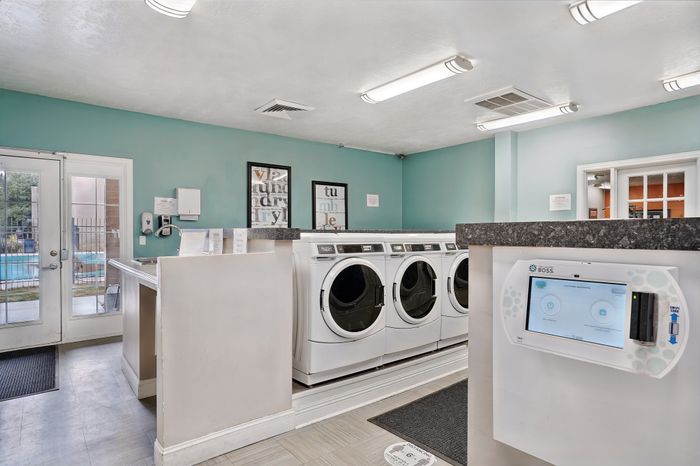 Bright and modern laundry room with multiple washers with a pool view for a convenient living experience.