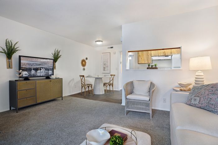 Elegant open-plan living area with a stylish dining nook, and a peek into a modern kitchen.