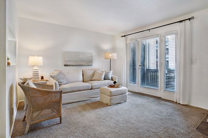 Inviting living room with elegant lighting, and bright natural light streaming through large windows and patio door.