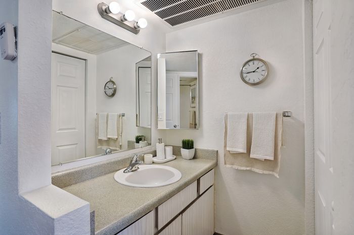 Modern bathroom with sleek countertop, large mirror, and elegant lighting.