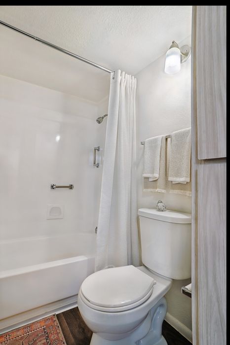 Bright and airy bathroom featuring a sleek white bathtub, shower and elegant lighting.