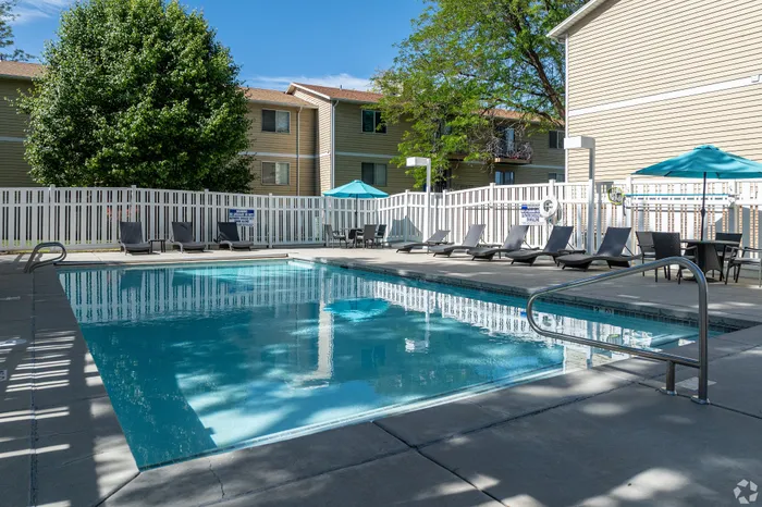 Inviting outdoor pool area with sleek lounge chairs and umbrellas, perfect for relaxation and enjoyment.